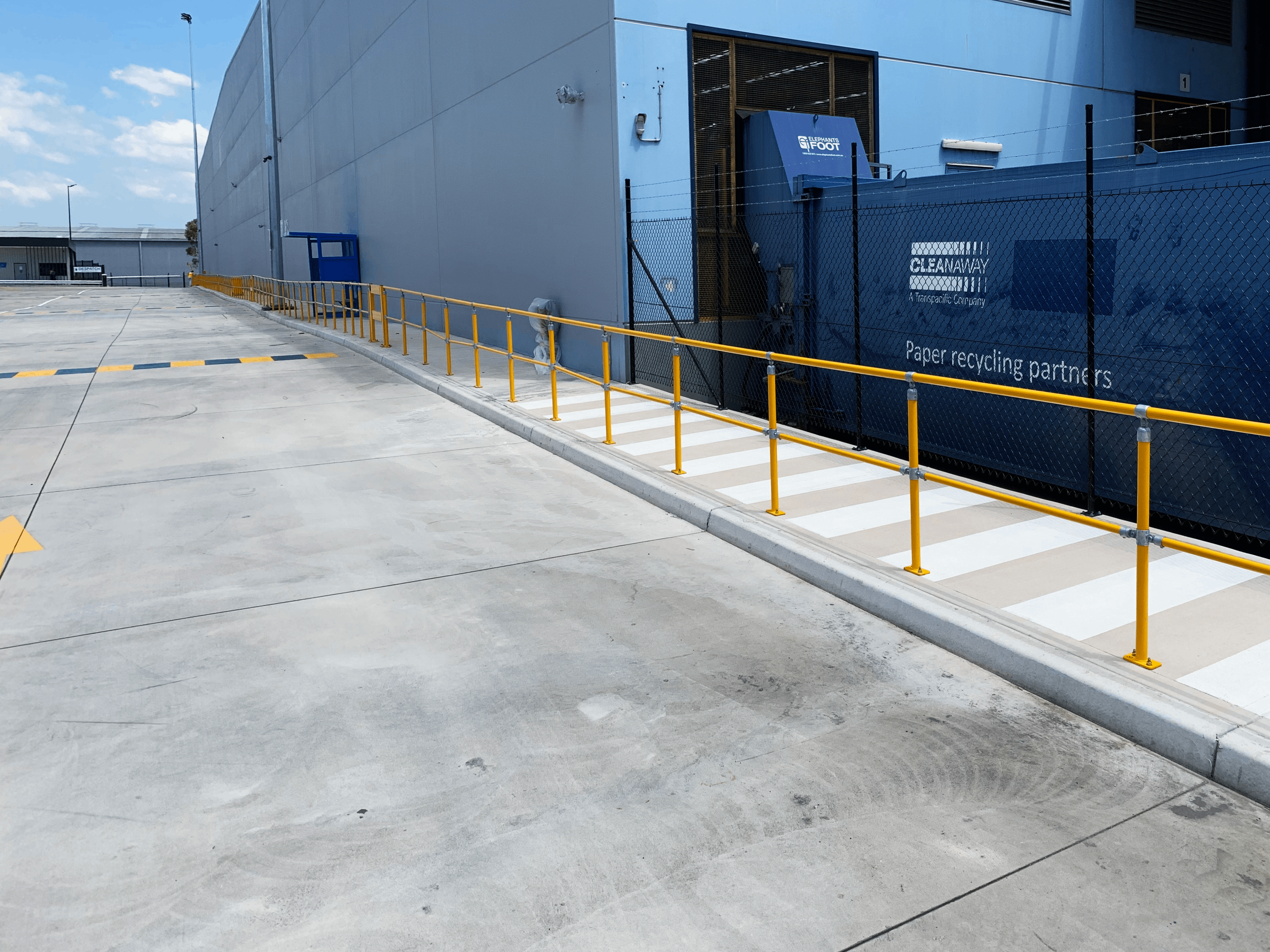 Industrial warehouse with yellow safety railings and recycling compactor