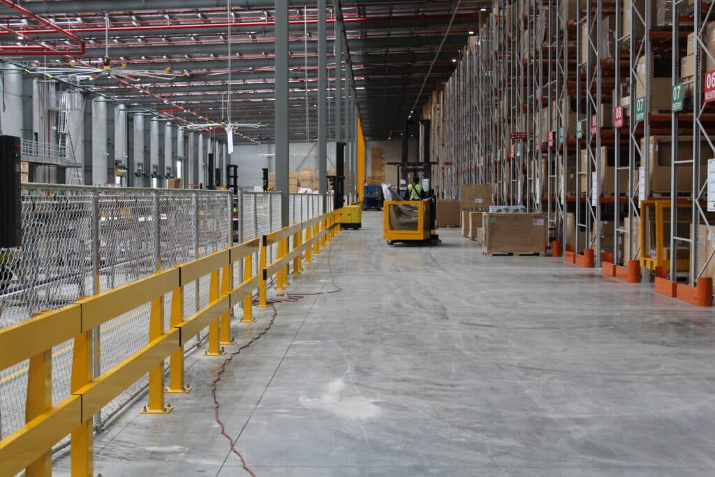 Spacious warehouse interior with safety barriers and equipment.