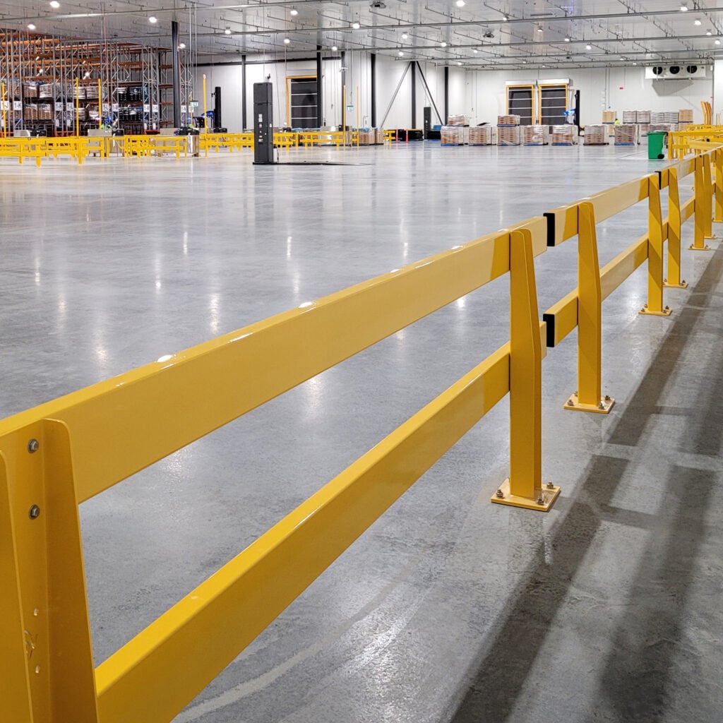 Yellow safety barriers in a spacious warehouse interior.