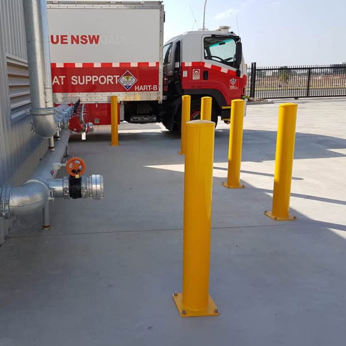 Yellow bollards near a fire truck in parking area.