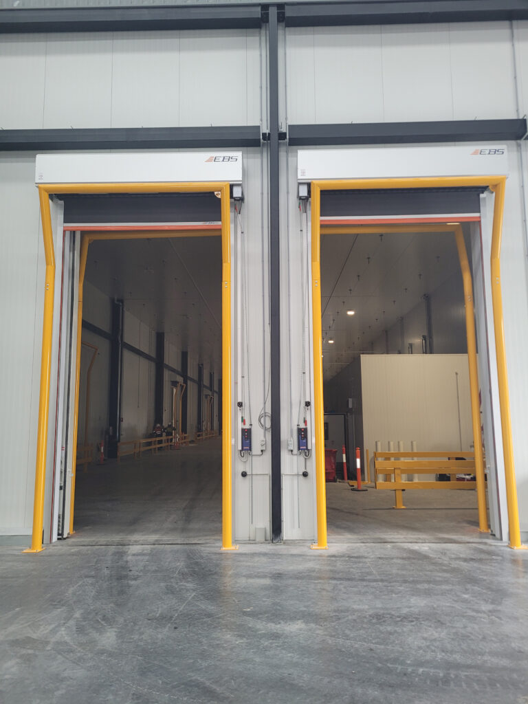 Two warehouse doors with yellow frames open.