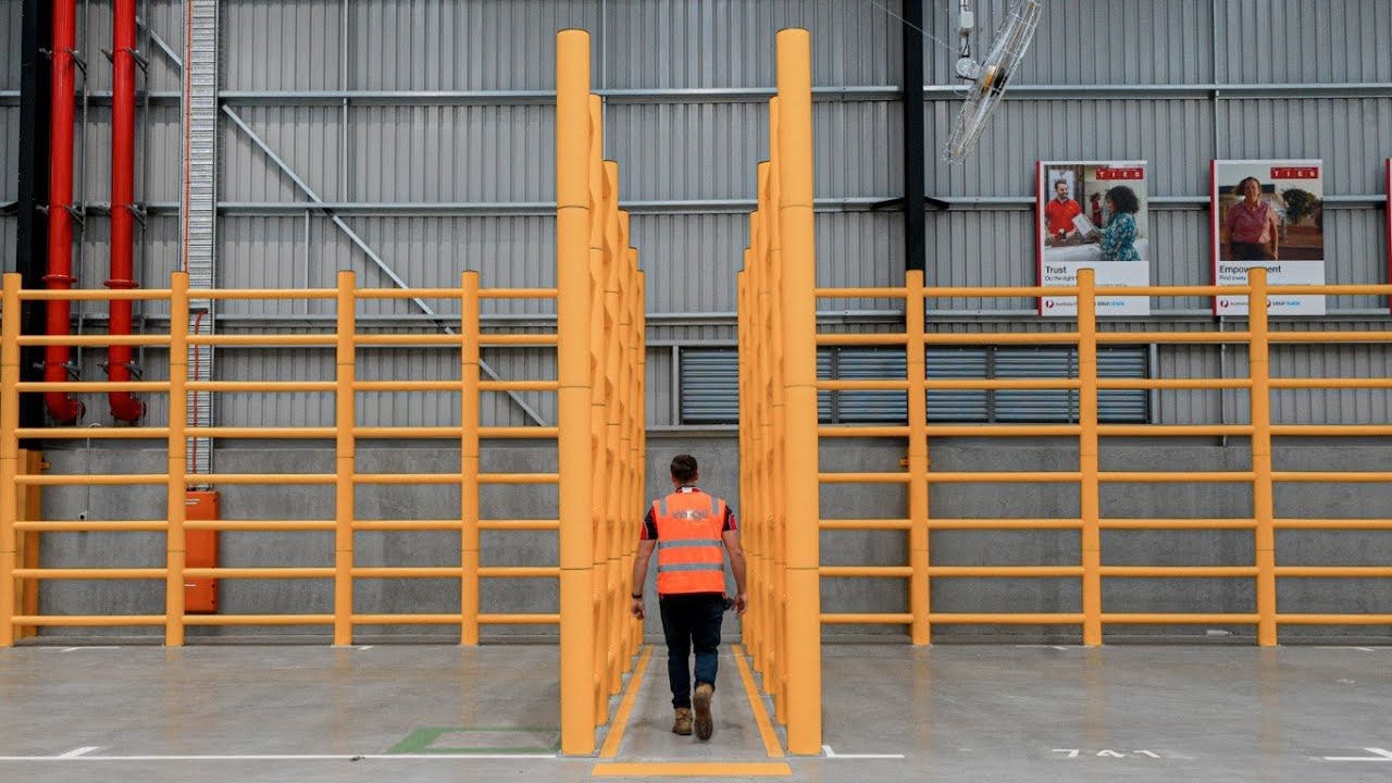 Warehouse worker navigating through yellow barriers.