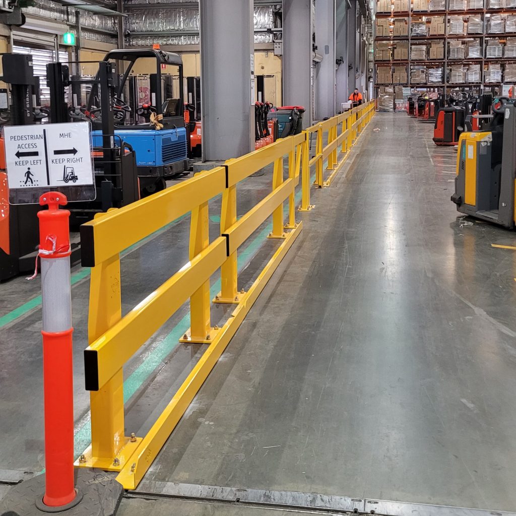 Industrial pathway with yellow safety barriers and signage