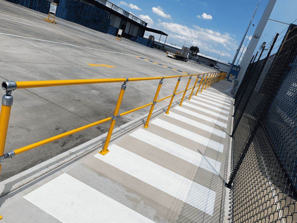 Yellow safety railing along a pedestrian pathway.