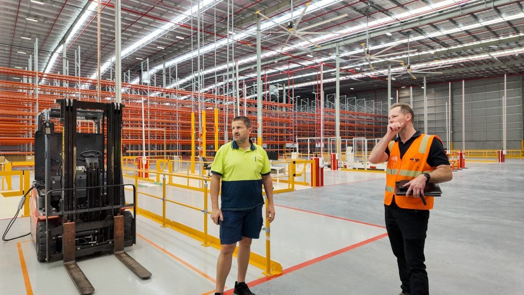Warehouse workers discuss operations near a forklift.