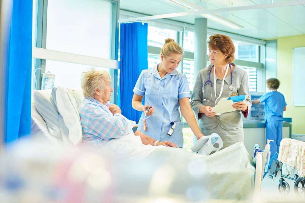 Nurses attending to a patient in a hospital room.