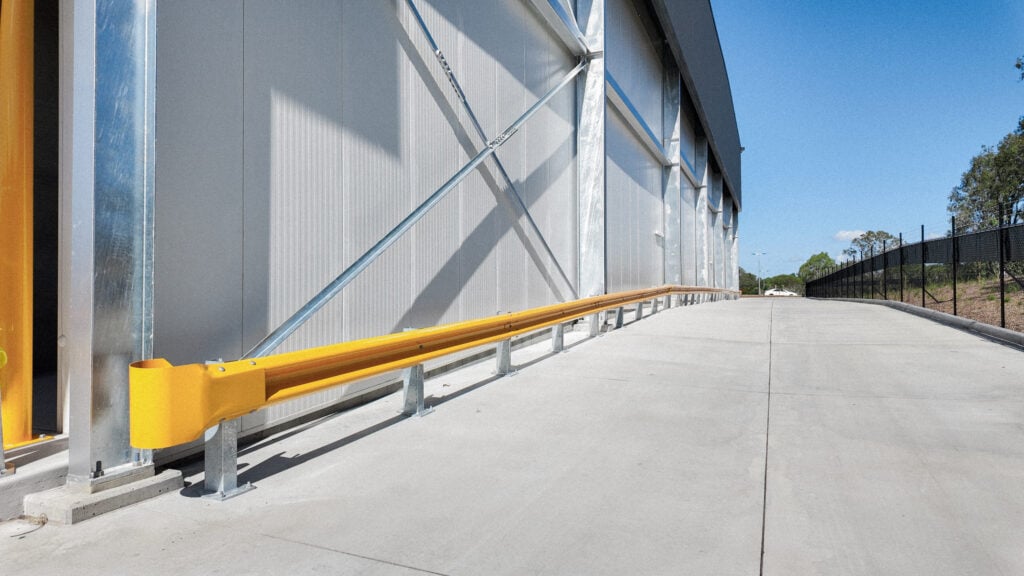 Yellow safety barrier alongside a concrete pathway.
