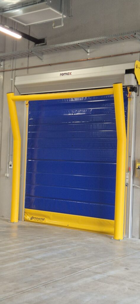 Blue industrial roller door with yellow safety barriers
