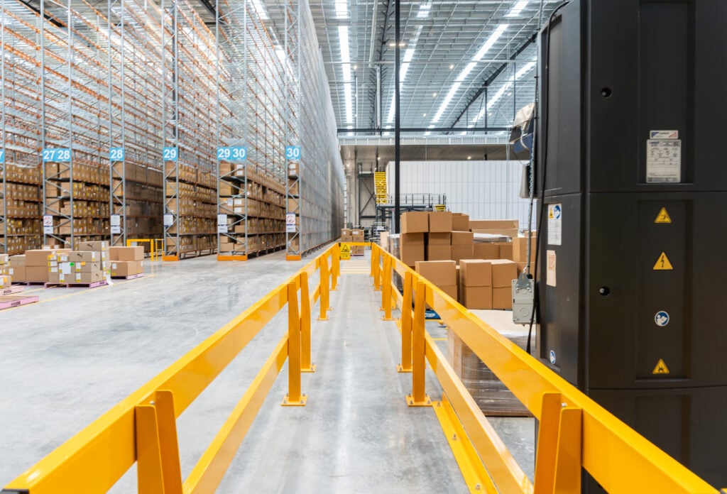 Long barrier-lined walkway running between racking into the distance.
